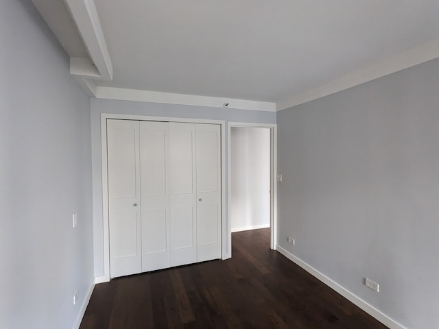 unfurnished bedroom with dark hardwood / wood-style flooring and a closet