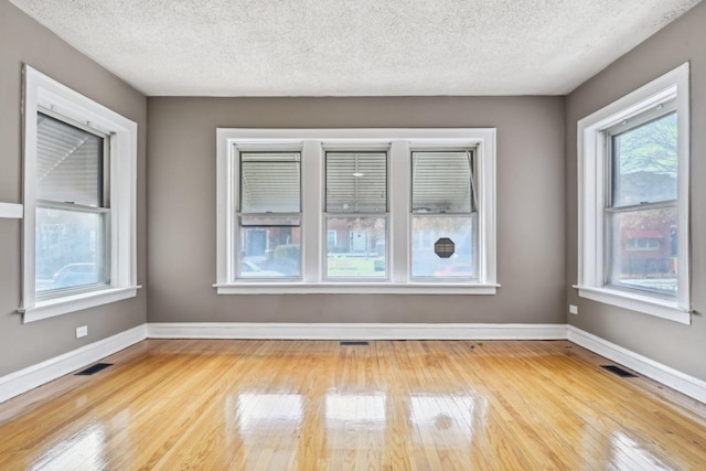 unfurnished room with a textured ceiling and light wood-type flooring