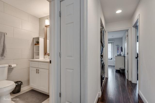 hall with dark hardwood / wood-style flooring and stacked washer and clothes dryer