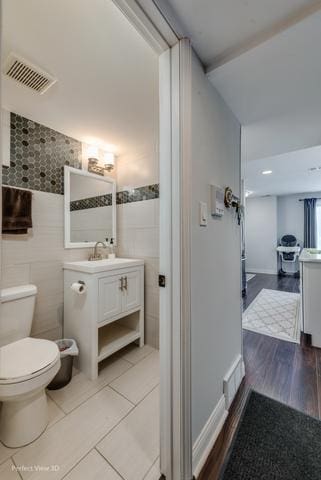 bathroom with tile patterned flooring, vanity, tile walls, and toilet