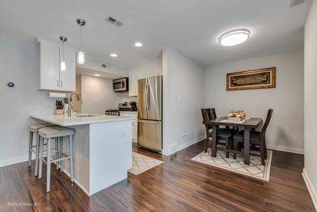 kitchen with pendant lighting, white cabinets, sink, kitchen peninsula, and stainless steel appliances