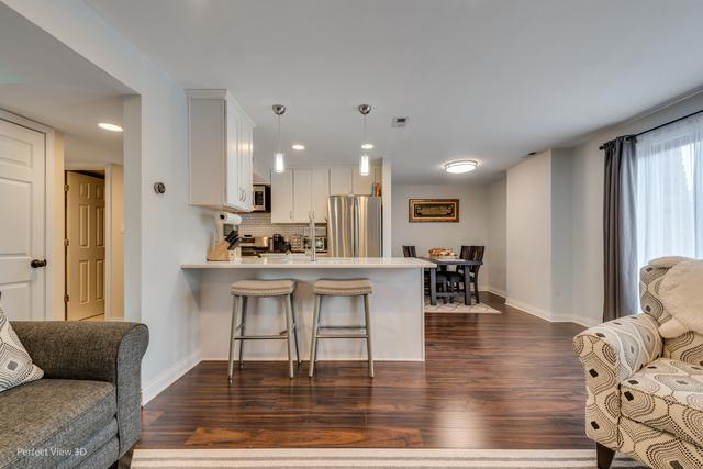 kitchen with pendant lighting, kitchen peninsula, appliances with stainless steel finishes, white cabinetry, and a breakfast bar area