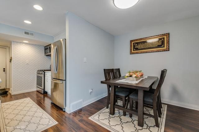 dining room featuring dark hardwood / wood-style floors and brick wall