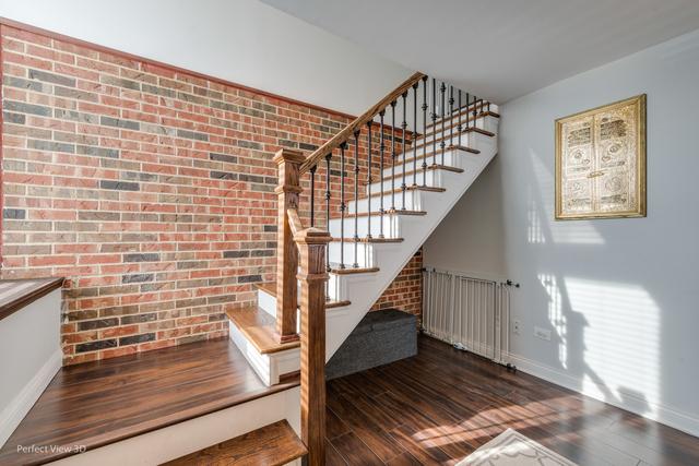 stairway with brick wall, wood-type flooring, and radiator