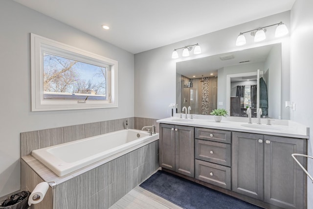 bathroom featuring vanity and tiled tub