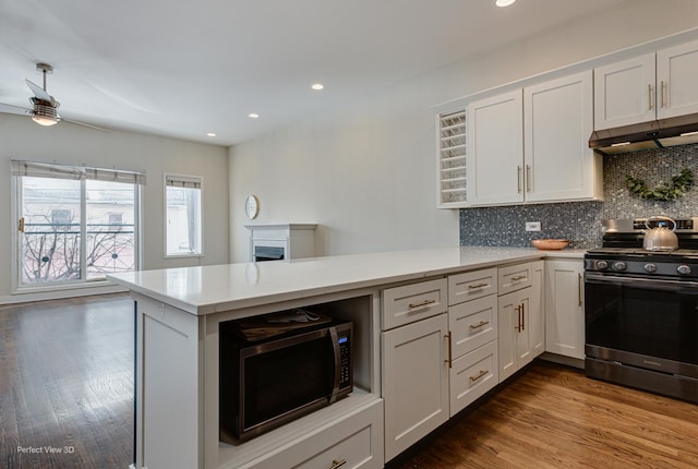 kitchen featuring gas range, tasteful backsplash, white cabinetry, and kitchen peninsula