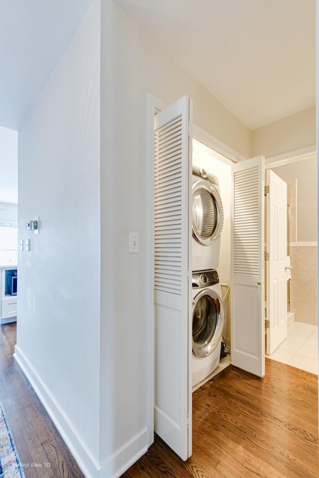 laundry room featuring light hardwood / wood-style flooring and stacked washer and clothes dryer