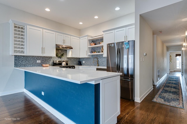 kitchen featuring stainless steel appliances, white cabinets, tasteful backsplash, kitchen peninsula, and dark hardwood / wood-style floors