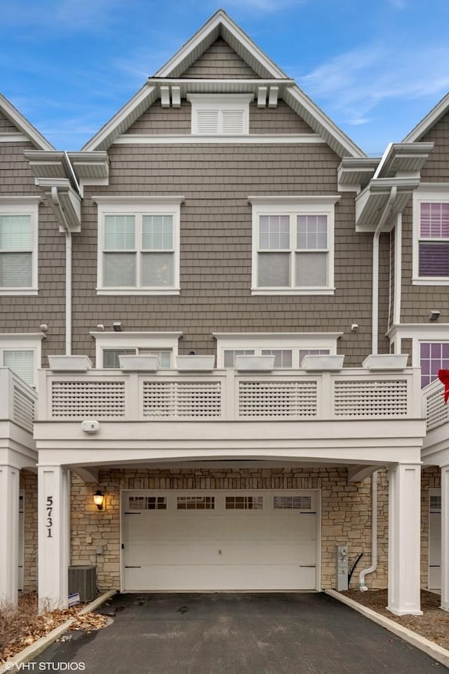 view of property with a balcony, a garage, and central AC unit