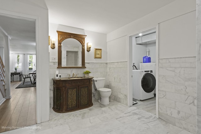 bathroom with vanity, washer / clothes dryer, toilet, and tile walls