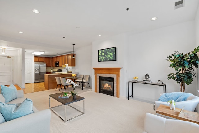 carpeted living room featuring a tile fireplace