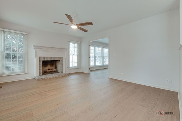 unfurnished living room with ceiling fan, a fireplace, and light wood-type flooring