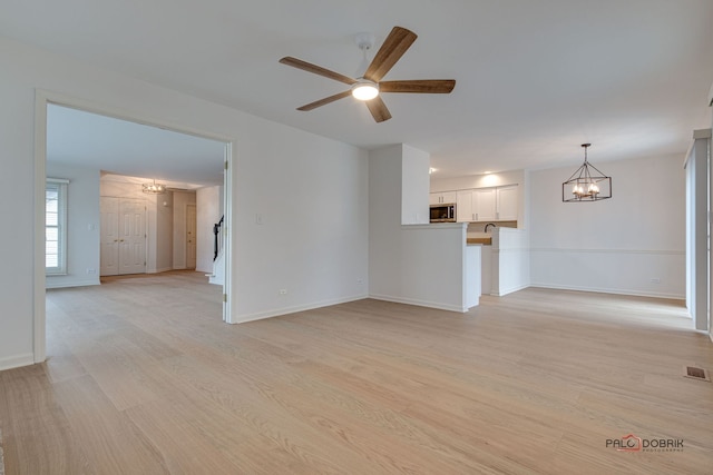 unfurnished living room with light hardwood / wood-style flooring and ceiling fan with notable chandelier