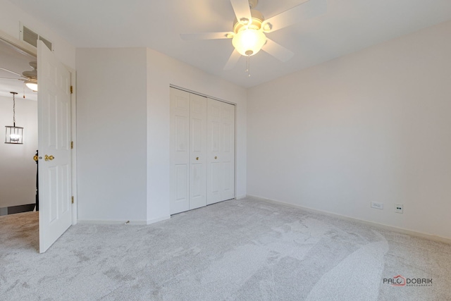 unfurnished bedroom featuring ceiling fan, a closet, and light carpet