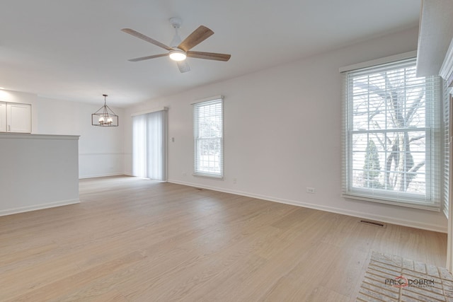 spare room featuring ceiling fan with notable chandelier and light hardwood / wood-style flooring