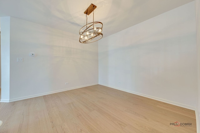 spare room with an inviting chandelier and light wood-type flooring