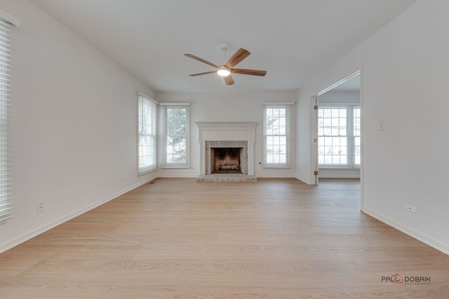 unfurnished living room featuring ceiling fan, light wood-type flooring, and a brick fireplace