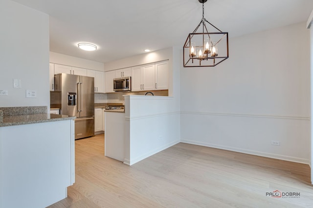 kitchen featuring white cabinetry, stainless steel appliances, a chandelier, decorative light fixtures, and light wood-type flooring