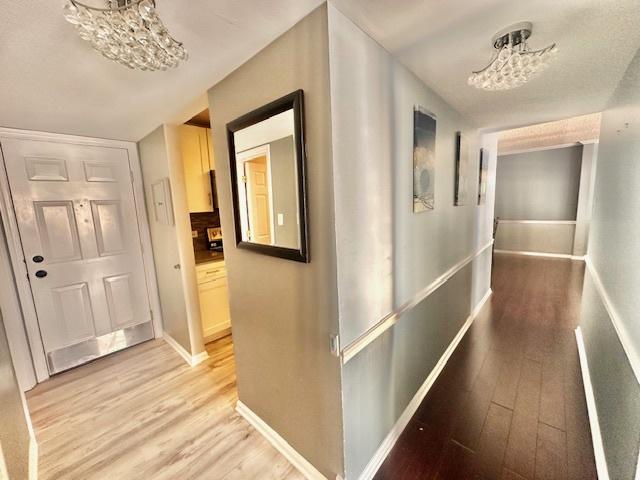 corridor featuring a notable chandelier and light wood-type flooring