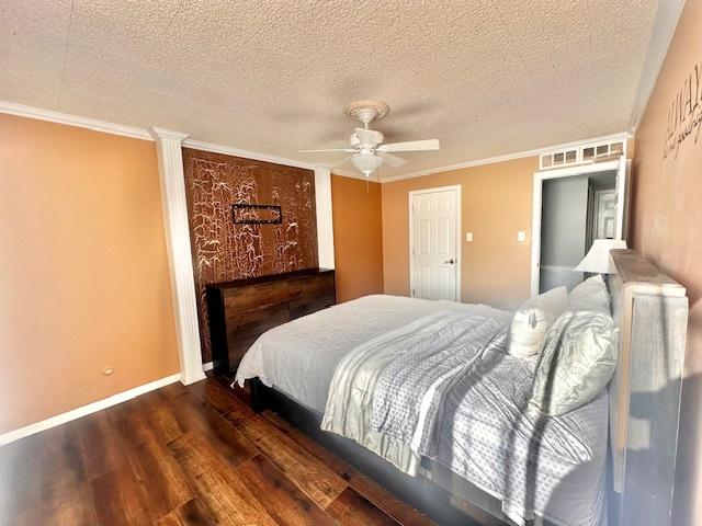 bedroom with dark hardwood / wood-style flooring, ceiling fan, crown molding, and a textured ceiling