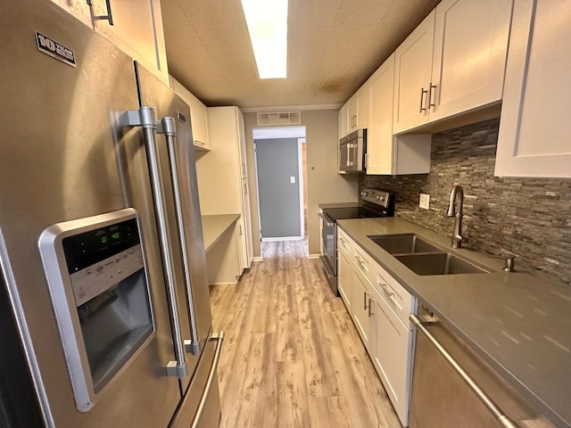 kitchen with decorative backsplash, white cabinetry, sink, and stainless steel appliances