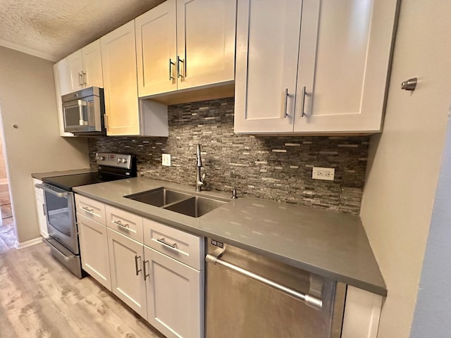 kitchen featuring white cabinets, appliances with stainless steel finishes, a textured ceiling, and sink