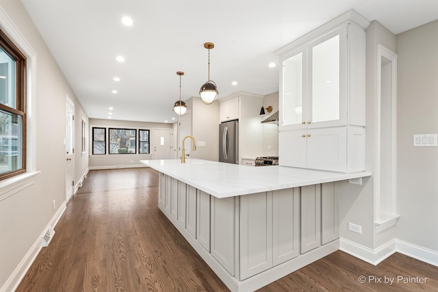 kitchen with white cabinetry, stainless steel appliances, dark hardwood / wood-style flooring, decorative light fixtures, and kitchen peninsula