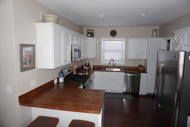 kitchen featuring butcher block counters, sink, white cabinets, and appliances with stainless steel finishes