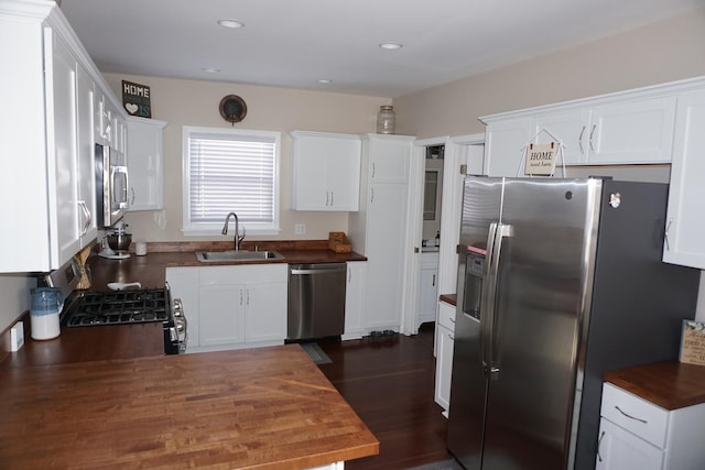 kitchen featuring appliances with stainless steel finishes, dark hardwood / wood-style floors, sink, and white cabinets