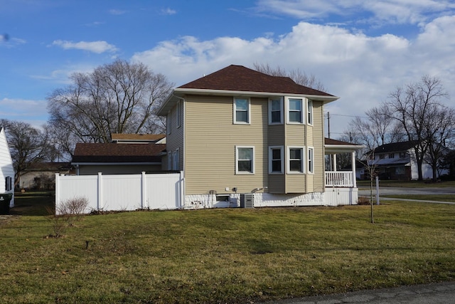 view of side of home featuring covered porch and a lawn