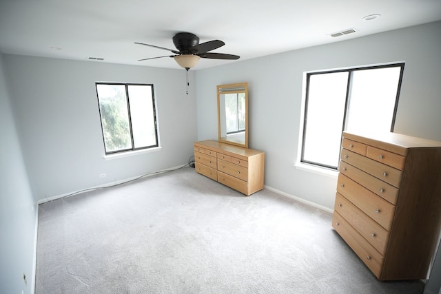 unfurnished bedroom featuring multiple windows, ceiling fan, and light carpet