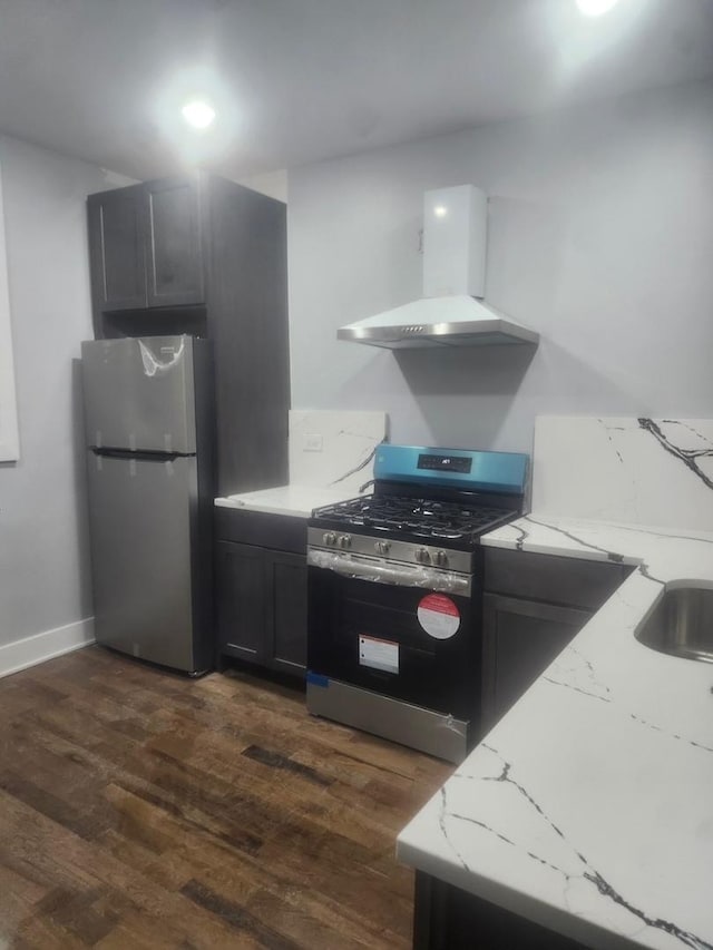 kitchen with light stone counters, stainless steel appliances, dark wood-type flooring, and range hood