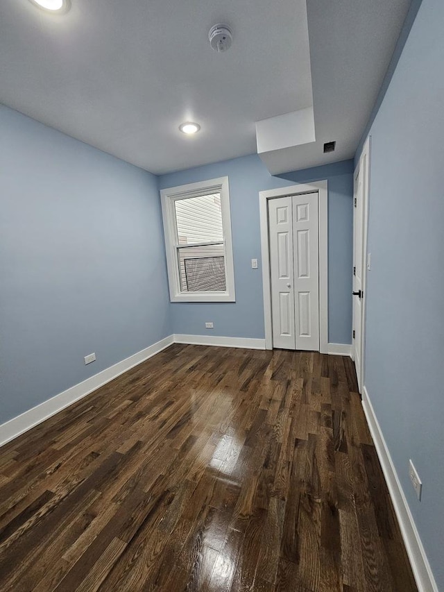 unfurnished bedroom with a closet and dark wood-type flooring