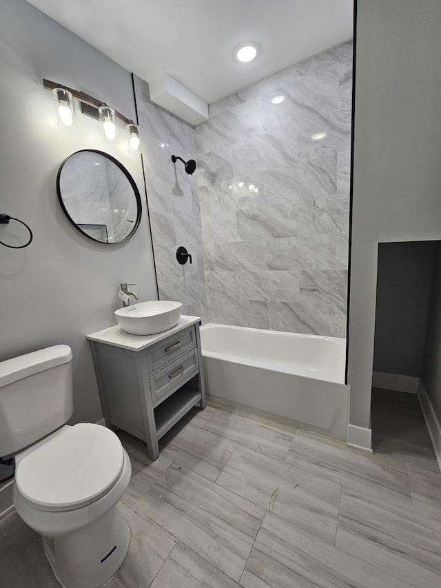 full bathroom featuring toilet, tiled shower / bath, and vanity