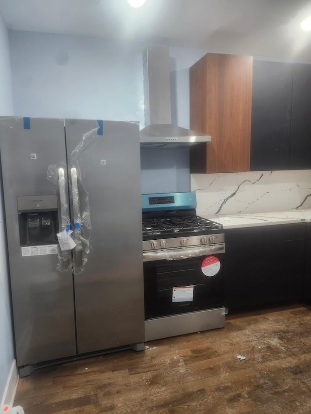 kitchen featuring stainless steel appliances, wall chimney range hood, and dark hardwood / wood-style floors