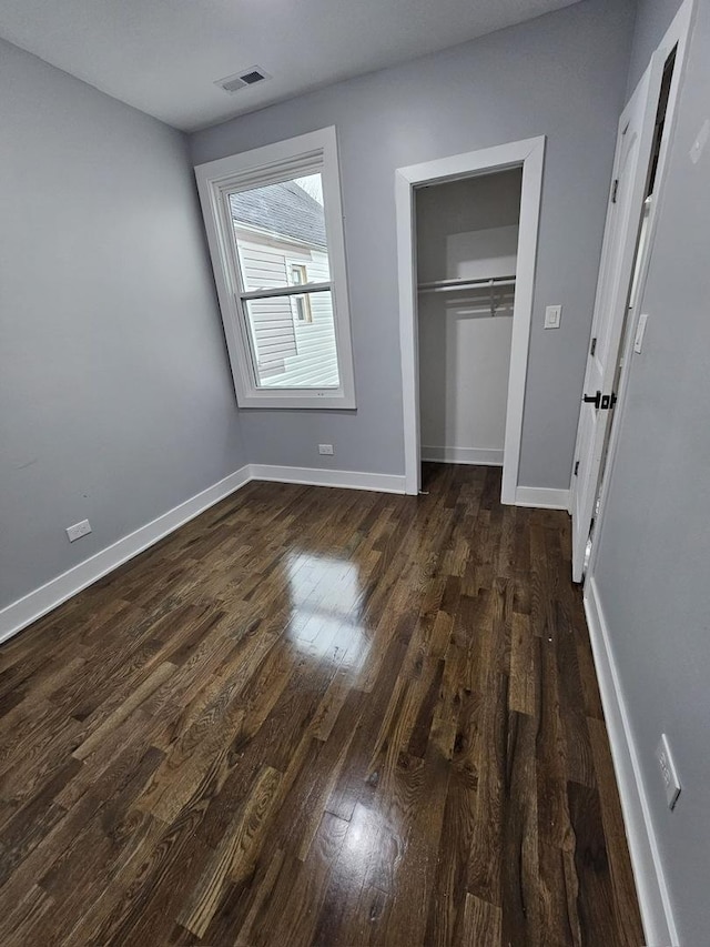 unfurnished bedroom featuring a closet and dark hardwood / wood-style floors