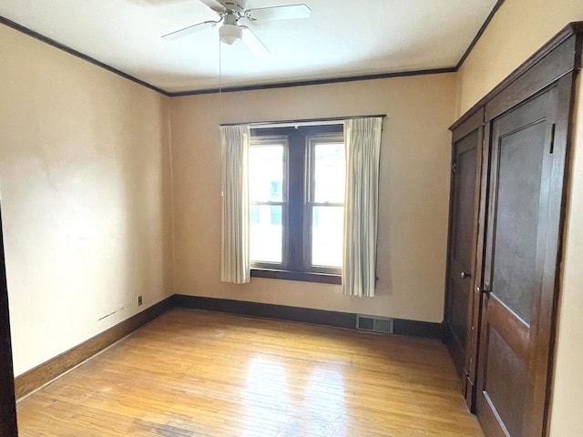 empty room with ceiling fan, crown molding, and light wood-type flooring