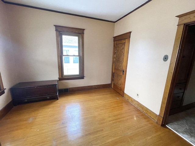 unfurnished room featuring crown molding and light wood-type flooring