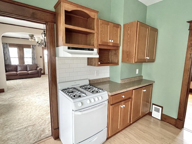 kitchen with white range, backsplash, light hardwood / wood-style flooring, and ceiling fan