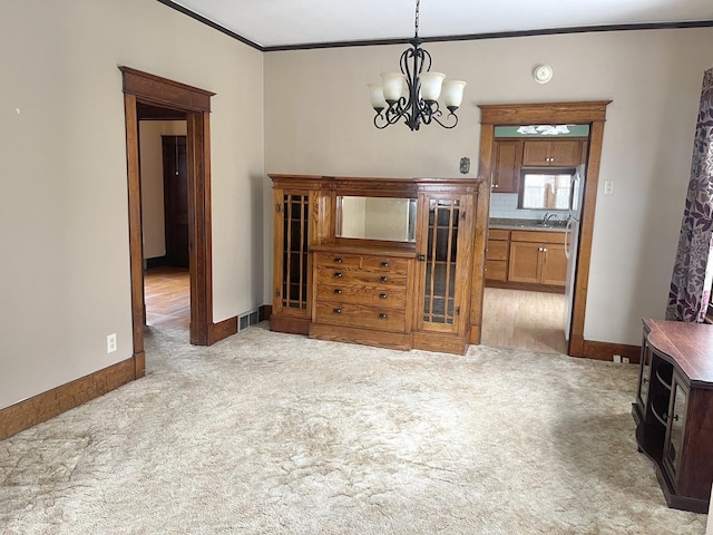 interior space with an inviting chandelier, crown molding, sink, and light carpet