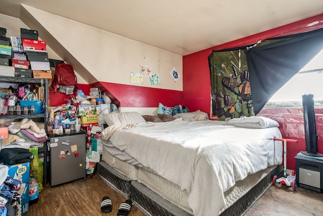 bedroom with hardwood / wood-style floors and refrigerator