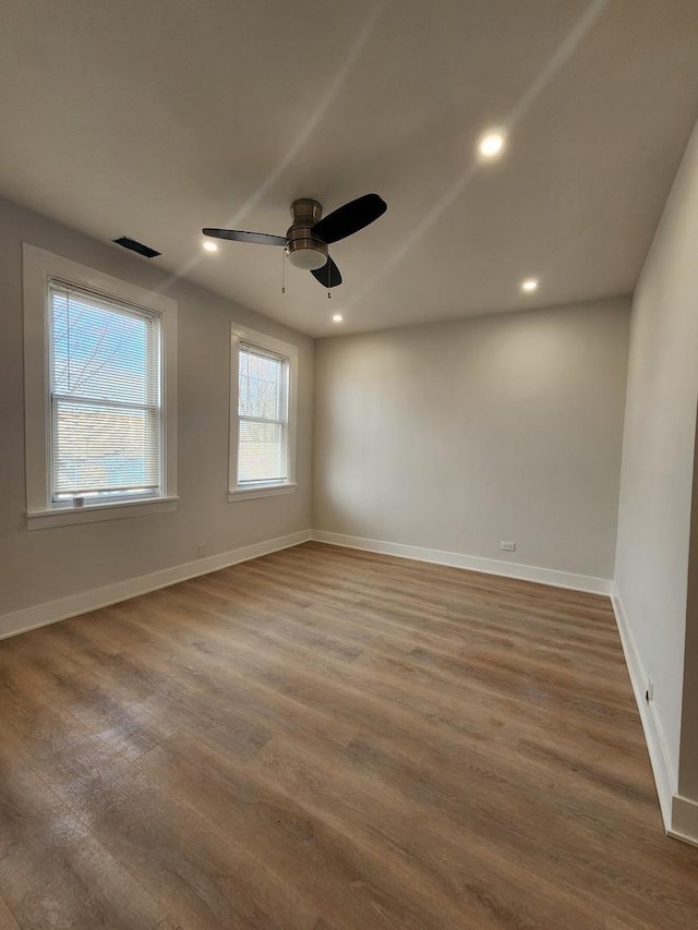 spare room featuring ceiling fan, dark hardwood / wood-style flooring, and plenty of natural light