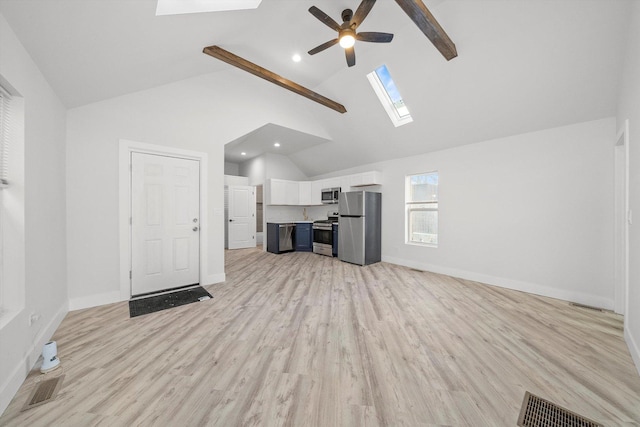 unfurnished living room with a skylight, ceiling fan, light wood-type flooring, high vaulted ceiling, and beamed ceiling