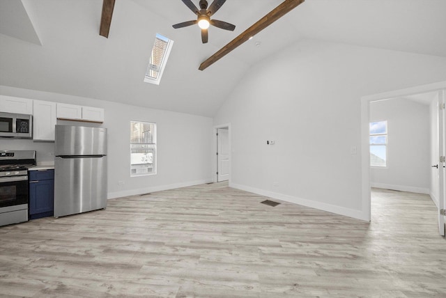 interior space featuring beam ceiling, appliances with stainless steel finishes, white cabinetry, and light hardwood / wood-style flooring