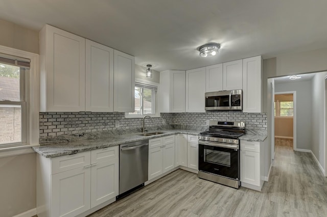 kitchen with white cabinetry, sink, stainless steel appliances, and light stone counters