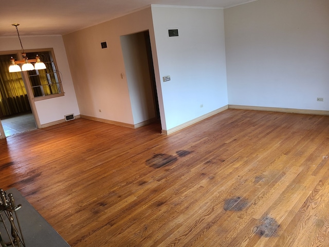 unfurnished room with hardwood / wood-style flooring and an inviting chandelier