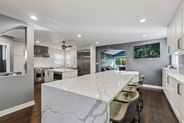 111 N Kenilworth Ave, Mount Prospect, IL 60056 - kitchen with wall chimney exhaust hood, a center island, dark wood-style flooring, tasteful backsplash, and high quality appliances