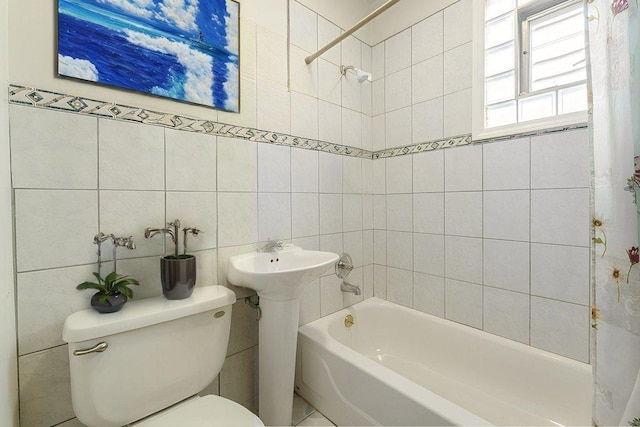 bathroom featuring tiled shower / bath combo, toilet, and tile walls