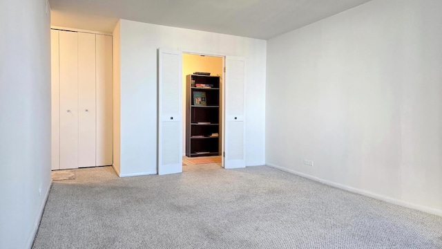 unfurnished bedroom featuring light carpet and a closet