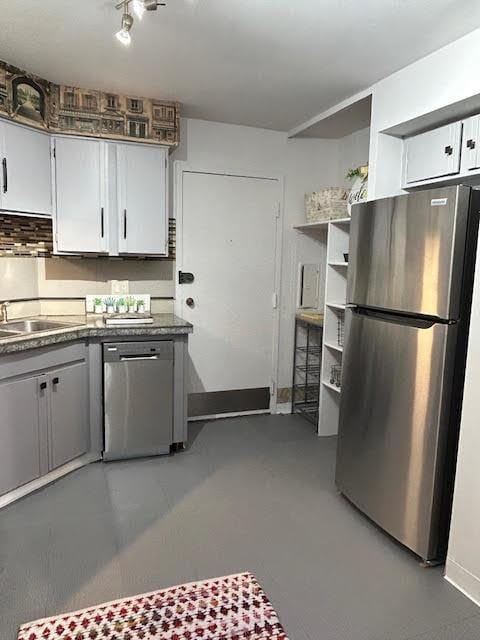 kitchen with white cabinetry, sink, concrete flooring, and appliances with stainless steel finishes